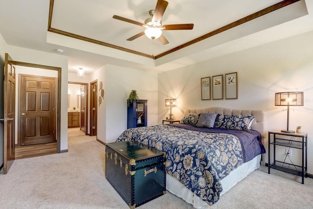 bedroom featuring ceiling fan, light carpet, ensuite bath, and a tray ceiling