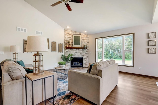 living room featuring high vaulted ceiling, a fireplace, ceiling fan, and light hardwood / wood-style floors