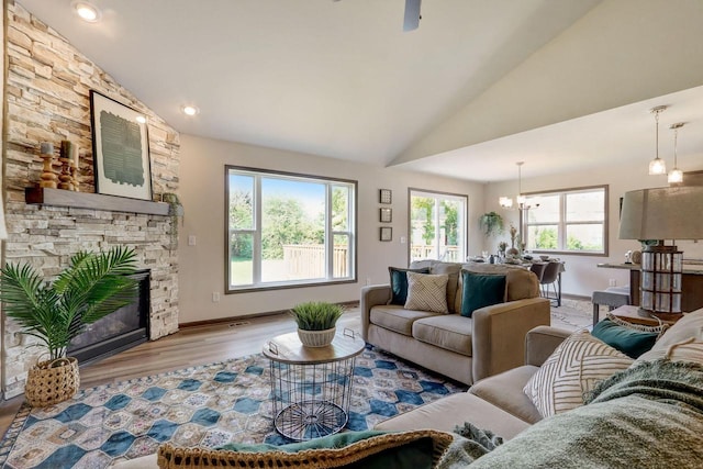 living room featuring high vaulted ceiling, a fireplace, a wealth of natural light, and light hardwood / wood-style floors