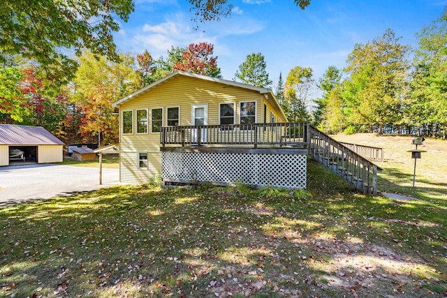 view of front of house with a deck, a front yard, and an outdoor structure