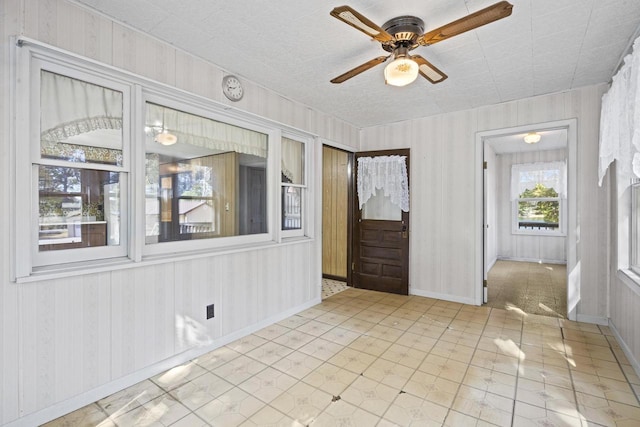 spare room featuring wooden walls and ceiling fan