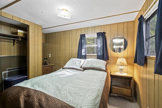 carpeted bedroom featuring wood walls, multiple windows, and a textured ceiling