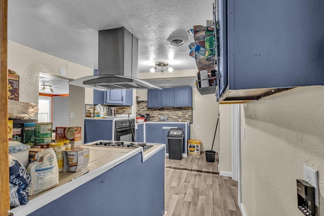 kitchen with island range hood, a textured ceiling, oven, blue cabinetry, and light wood-type flooring