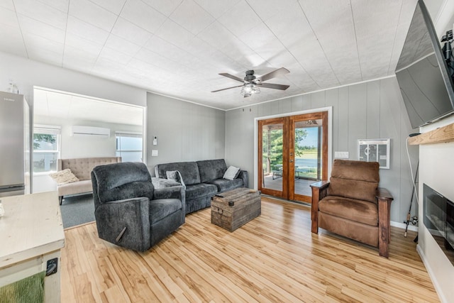 living room featuring light wood-type flooring, ceiling fan, a wall mounted air conditioner, and french doors