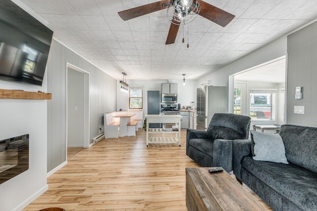 living room with wooden walls, ceiling fan, and light hardwood / wood-style floors