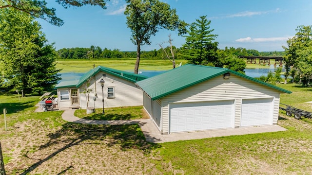 exterior space with a water view, a garage, an outdoor structure, and a front lawn