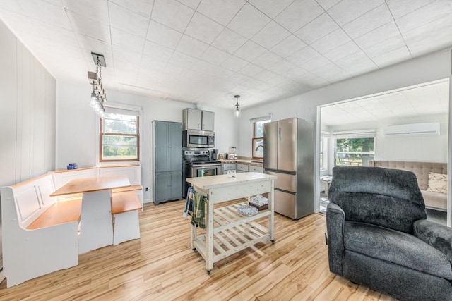 kitchen with pendant lighting, gray cabinetry, appliances with stainless steel finishes, light wood-type flooring, and a wall mounted air conditioner