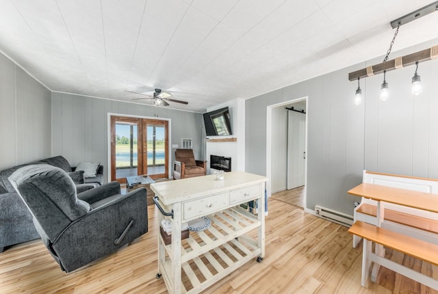 living room with ceiling fan, french doors, a baseboard heating unit, a barn door, and light hardwood / wood-style flooring