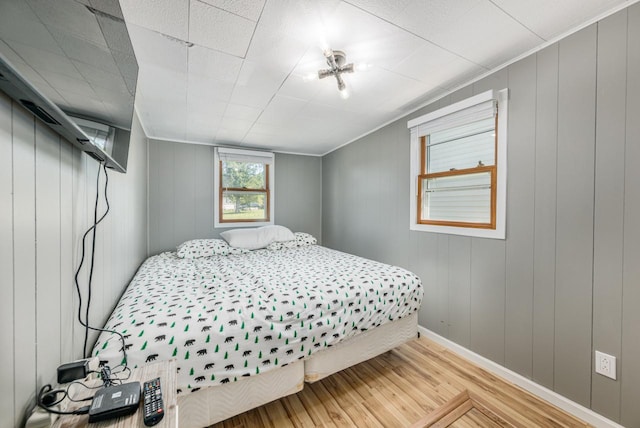 bedroom with hardwood / wood-style flooring and wooden walls