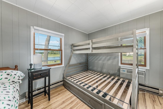 bedroom featuring wood-type flooring, a water view, and multiple windows