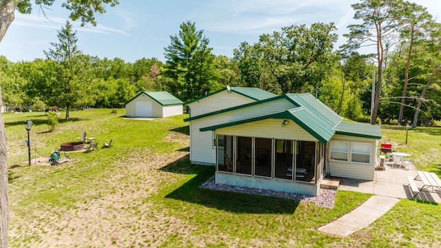 back of house with an outbuilding, a yard, a sunroom, and a fire pit