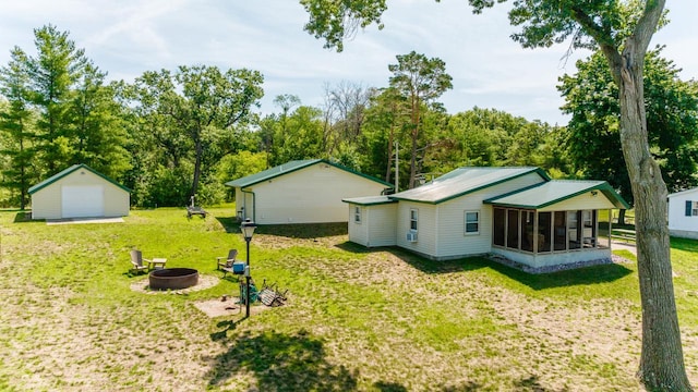 view of yard with an outdoor fire pit, a garage, a sunroom, and an outdoor structure