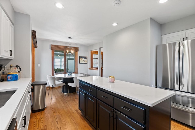 kitchen featuring stainless steel refrigerator, pendant lighting, a kitchen island, light hardwood / wood-style flooring, and white cabinetry