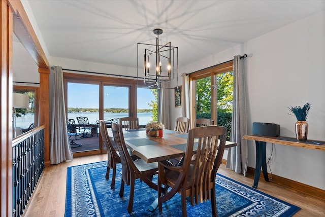 dining space with hardwood / wood-style flooring, a notable chandelier, and a water view