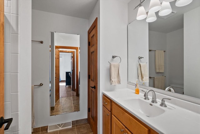 bathroom featuring tile patterned floors, an inviting chandelier, vanity, and toilet