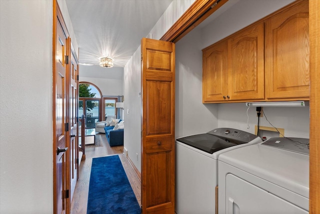 laundry area featuring washing machine and dryer, a chandelier, cabinets, and light wood-type flooring