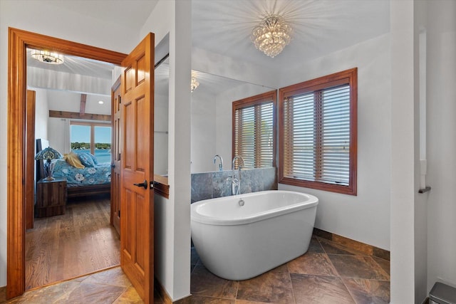 bathroom with hardwood / wood-style floors, a healthy amount of sunlight, a washtub, and a chandelier