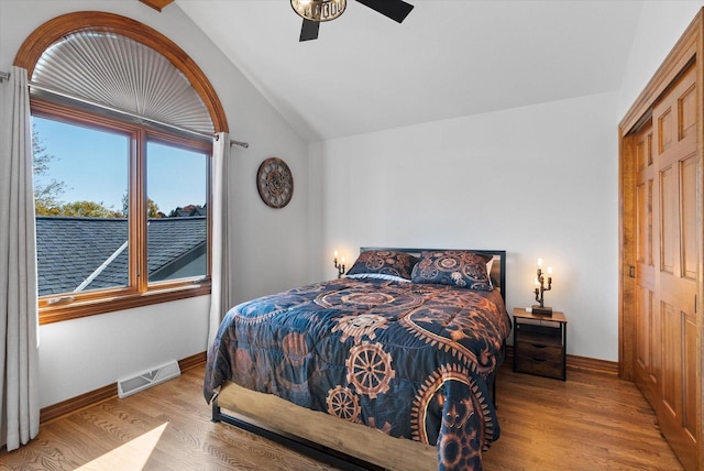 bedroom with ceiling fan, light hardwood / wood-style floors, a closet, and vaulted ceiling