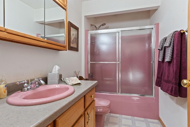 full bathroom featuring toilet, bath / shower combo with glass door, and vanity