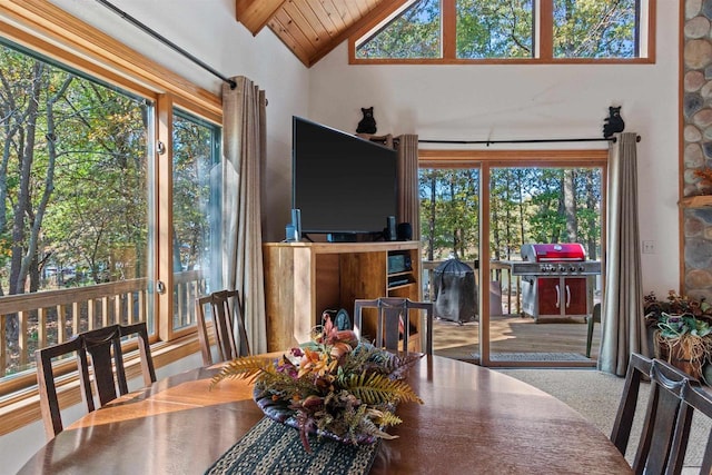 carpeted dining space featuring vaulted ceiling with beams, wooden ceiling, and a wealth of natural light