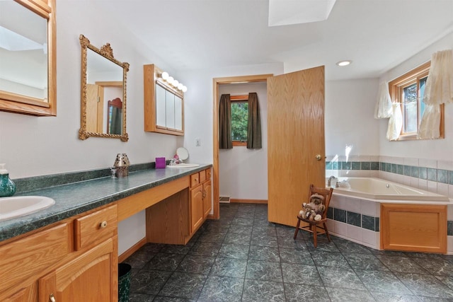 bathroom with tiled bath, vanity, and a wealth of natural light