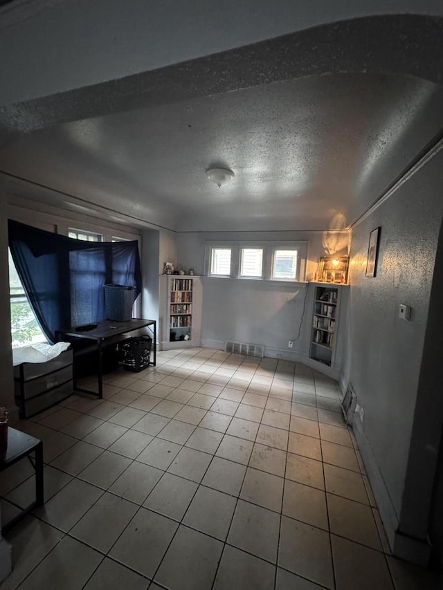 unfurnished living room with tile patterned floors, built in shelves, and a textured ceiling