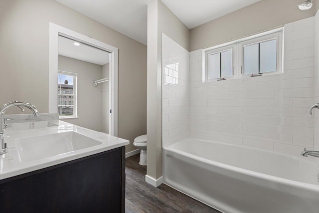 full bathroom featuring tiled shower / bath, hardwood / wood-style floors, vanity, and toilet