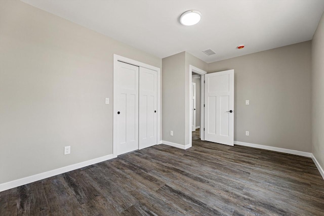 unfurnished bedroom featuring dark wood-type flooring and a closet