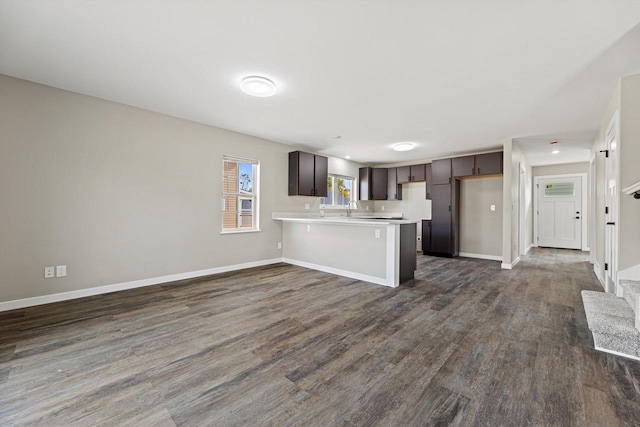 kitchen with dark hardwood / wood-style floors, sink, kitchen peninsula, dark brown cabinets, and a kitchen bar