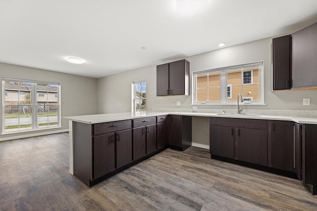 kitchen with kitchen peninsula, hardwood / wood-style floors, sink, and dark brown cabinets