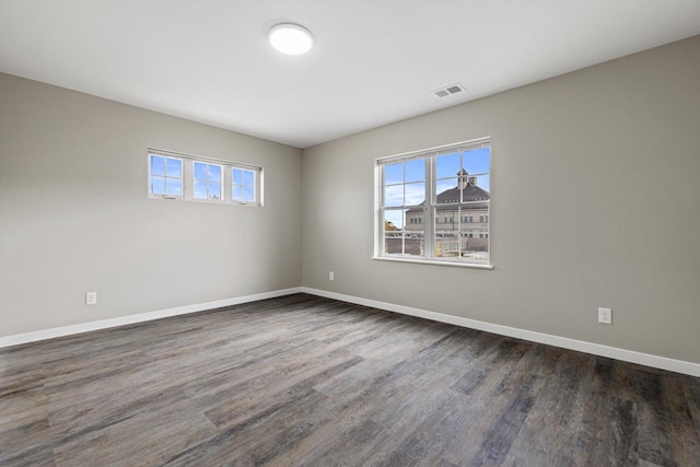 spare room featuring plenty of natural light and dark hardwood / wood-style floors