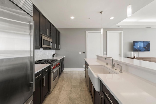 kitchen featuring high end appliances, hanging light fixtures, sink, and tasteful backsplash