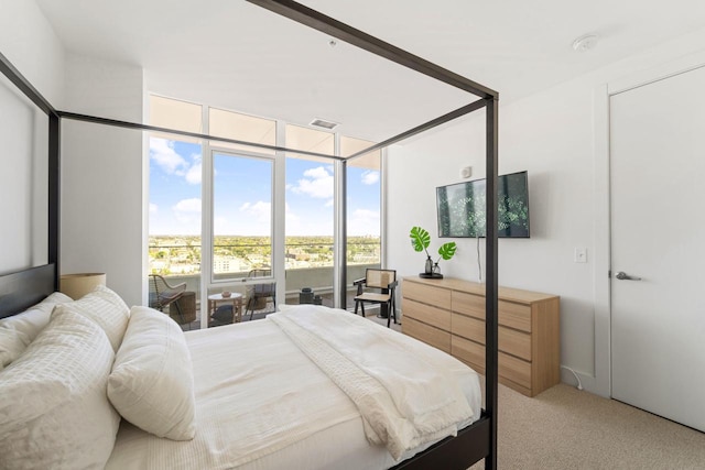 bedroom with visible vents, a wall of windows, and light colored carpet