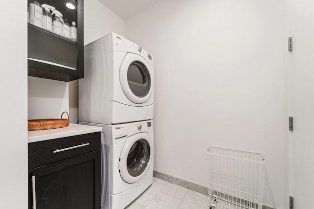 clothes washing area featuring cabinets and stacked washer / dryer