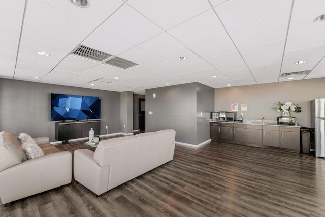 living room featuring a drop ceiling, dark hardwood / wood-style floors, and sink