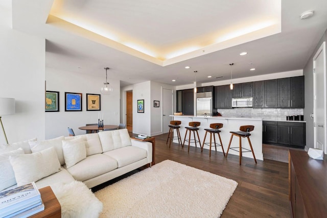 living room with dark wood-type flooring and a raised ceiling