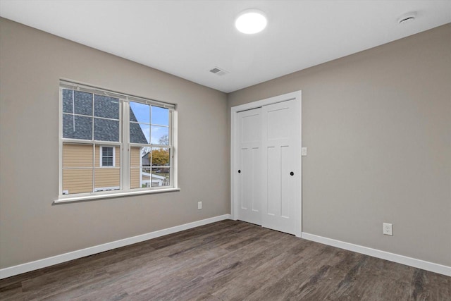 unfurnished bedroom with a closet and dark wood-type flooring