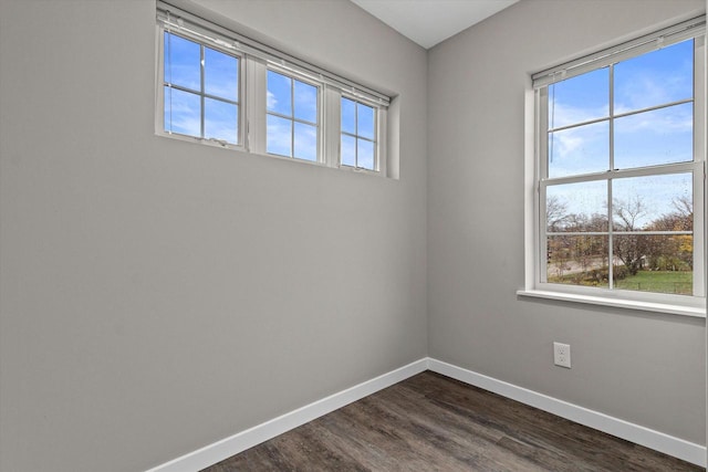 unfurnished room featuring a healthy amount of sunlight and dark hardwood / wood-style floors