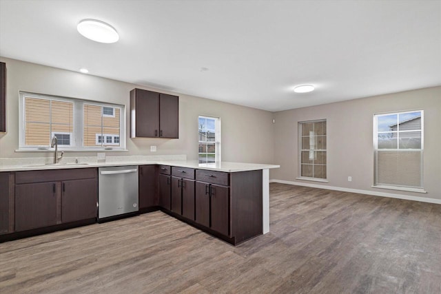 kitchen with stainless steel dishwasher, dark brown cabinetry, light wood-type flooring, and sink