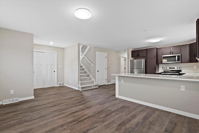 kitchen with kitchen peninsula, dark brown cabinetry, dark hardwood / wood-style flooring, and stainless steel appliances