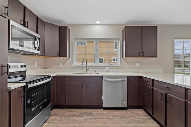 kitchen featuring sink, stainless steel appliances, dark brown cabinets, and light wood-type flooring