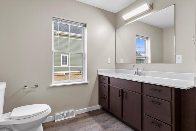 bathroom featuring vanity, hardwood / wood-style flooring, toilet, and a wealth of natural light