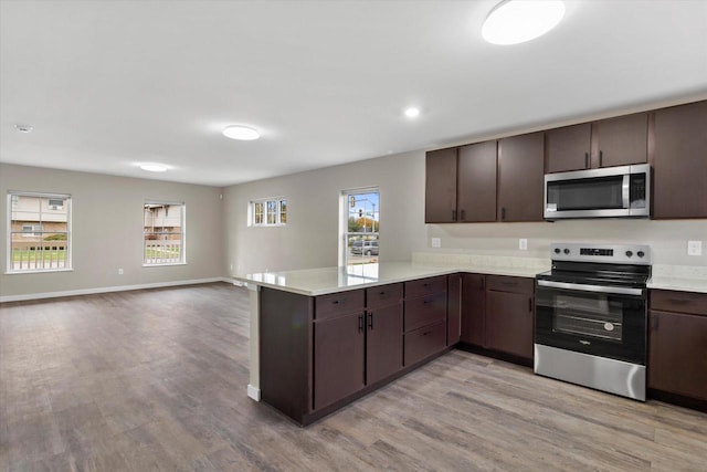 kitchen featuring kitchen peninsula, plenty of natural light, stainless steel appliances, and light hardwood / wood-style floors