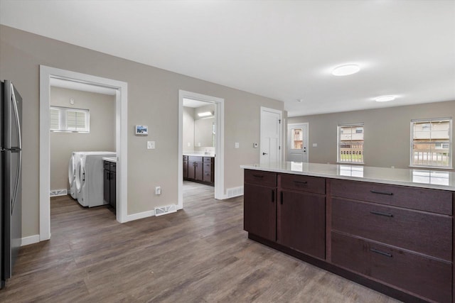 kitchen with dark brown cabinetry, washer and clothes dryer, and wood-type flooring