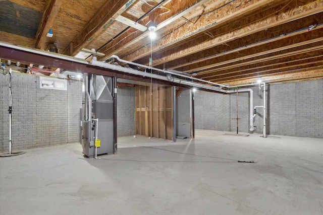 basement featuring heating unit and brick wall