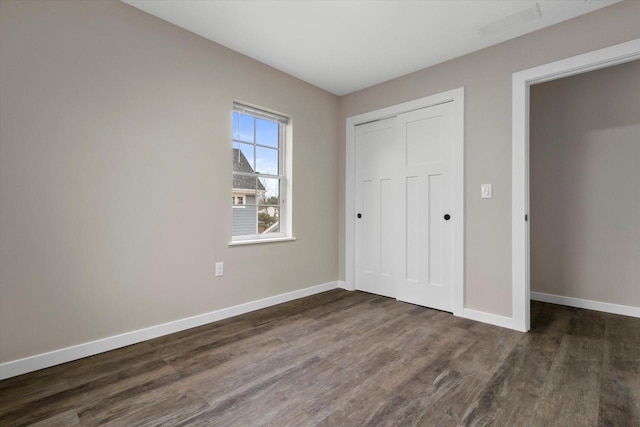 unfurnished bedroom featuring a closet and dark hardwood / wood-style floors