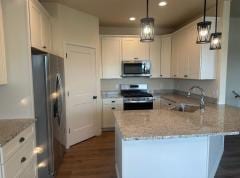 kitchen featuring light stone counters, decorative light fixtures, appliances with stainless steel finishes, and white cabinets