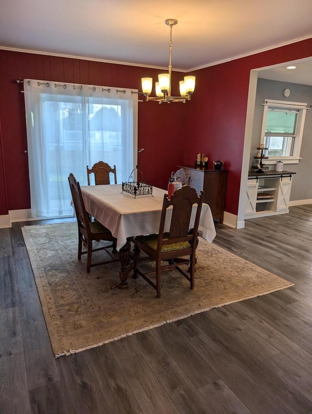 dining area featuring ornamental molding, dark wood-type flooring, and an inviting chandelier