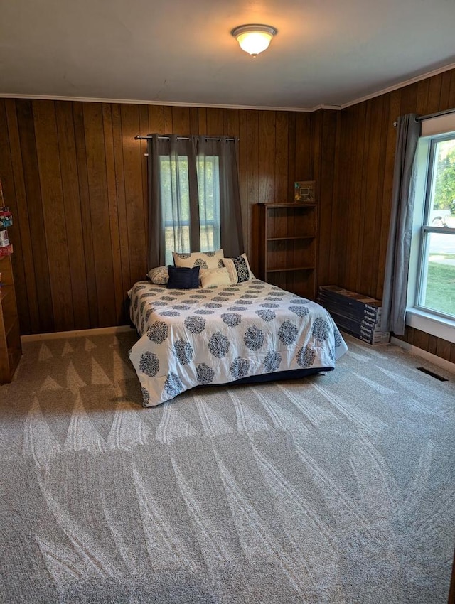 carpeted bedroom featuring wood walls and ornamental molding