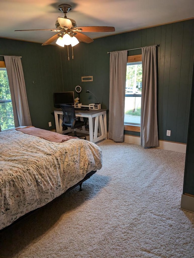 bedroom with ceiling fan, wood walls, and carpet